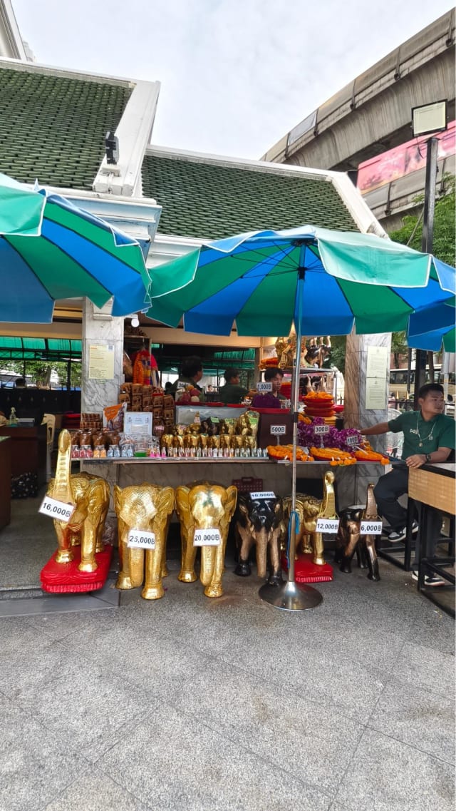 A vendor stall selling carved elephant statues and offerings near Erawan Shrine