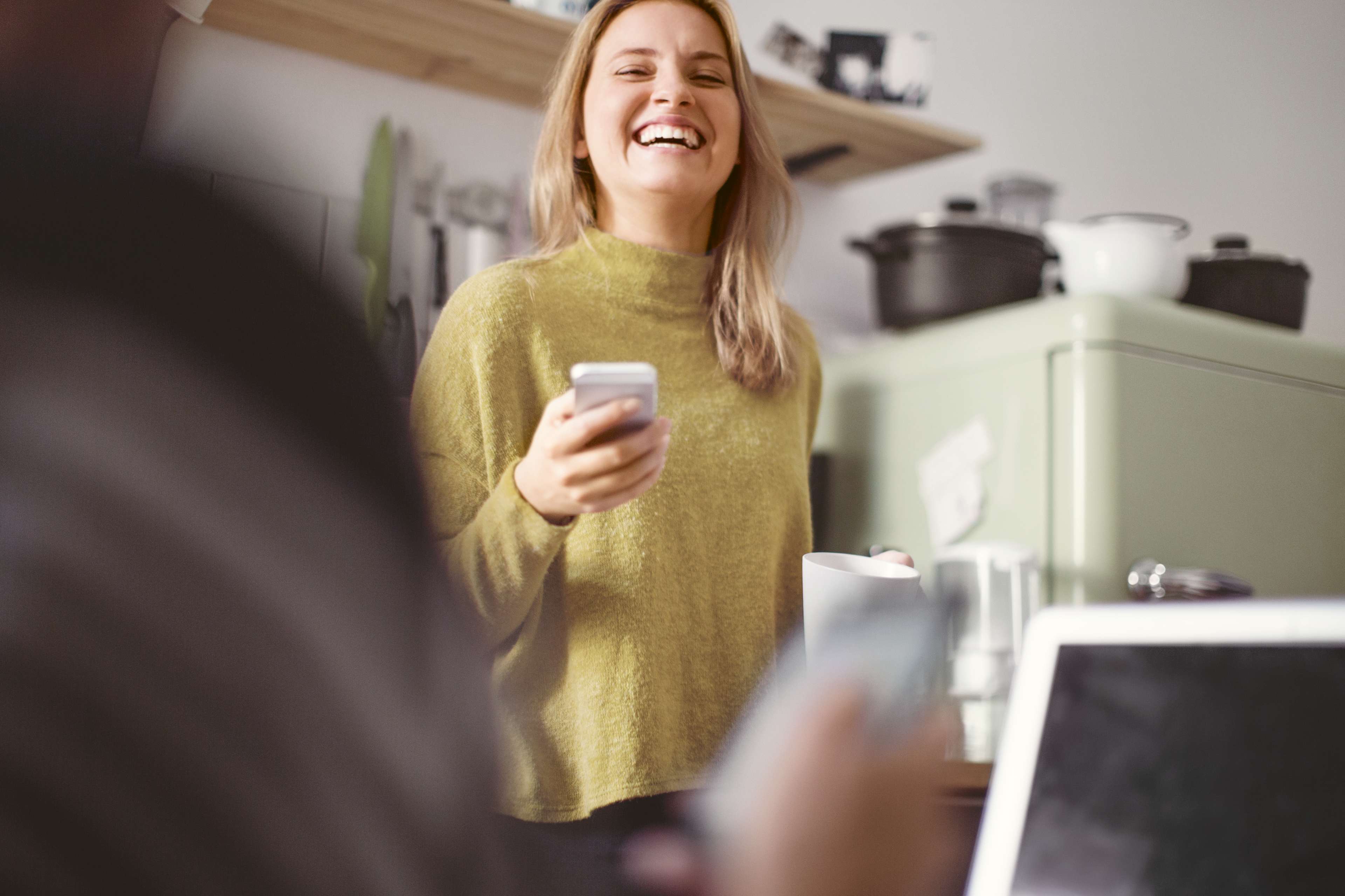 Kunden_Zuhause_Frau_Kueche_Smartphone_Lachen_s_kgfs5j
