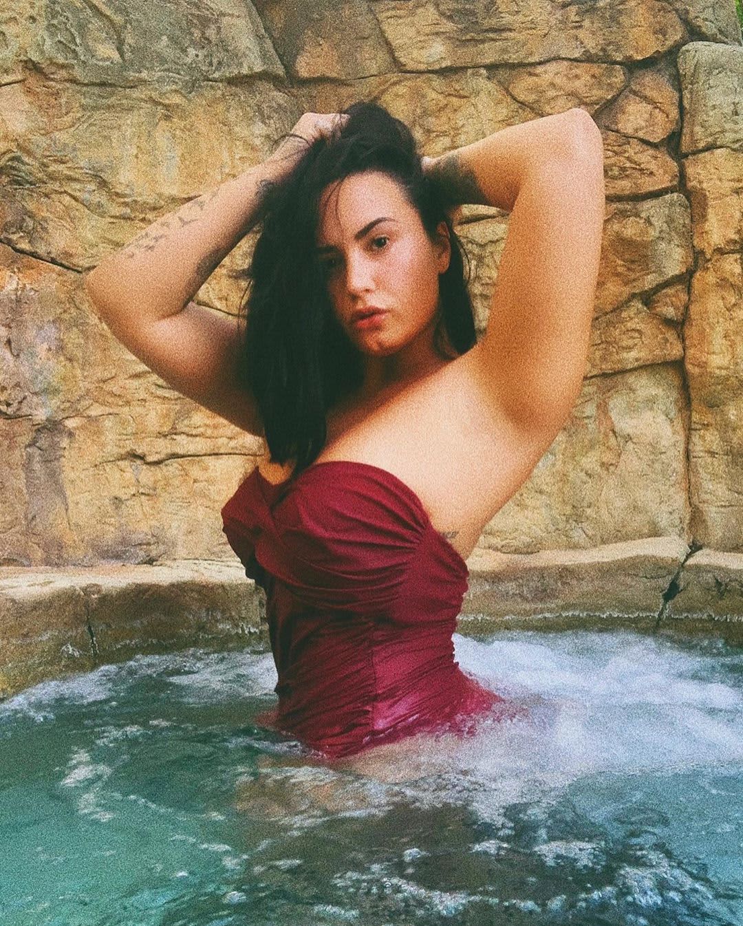 Demi Lovato wearing a purple swimsuit