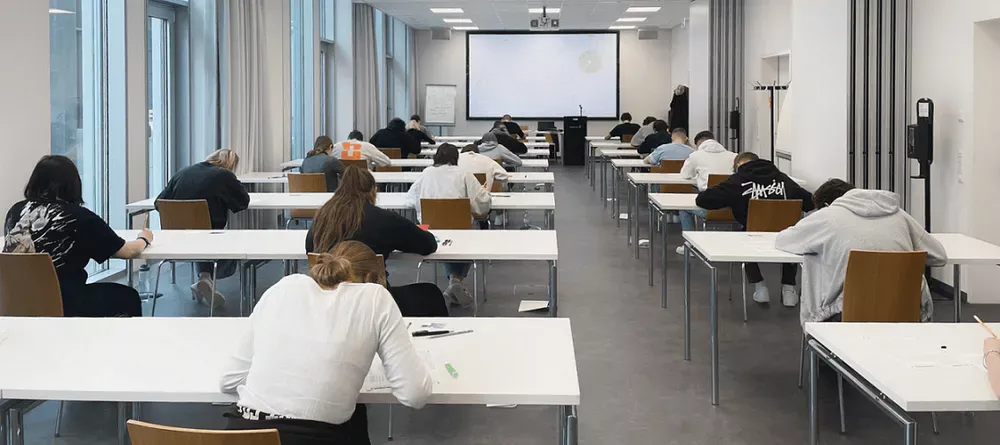 candidates sitting at desks and writing the Goethe exam, which can be used for the FIDE test