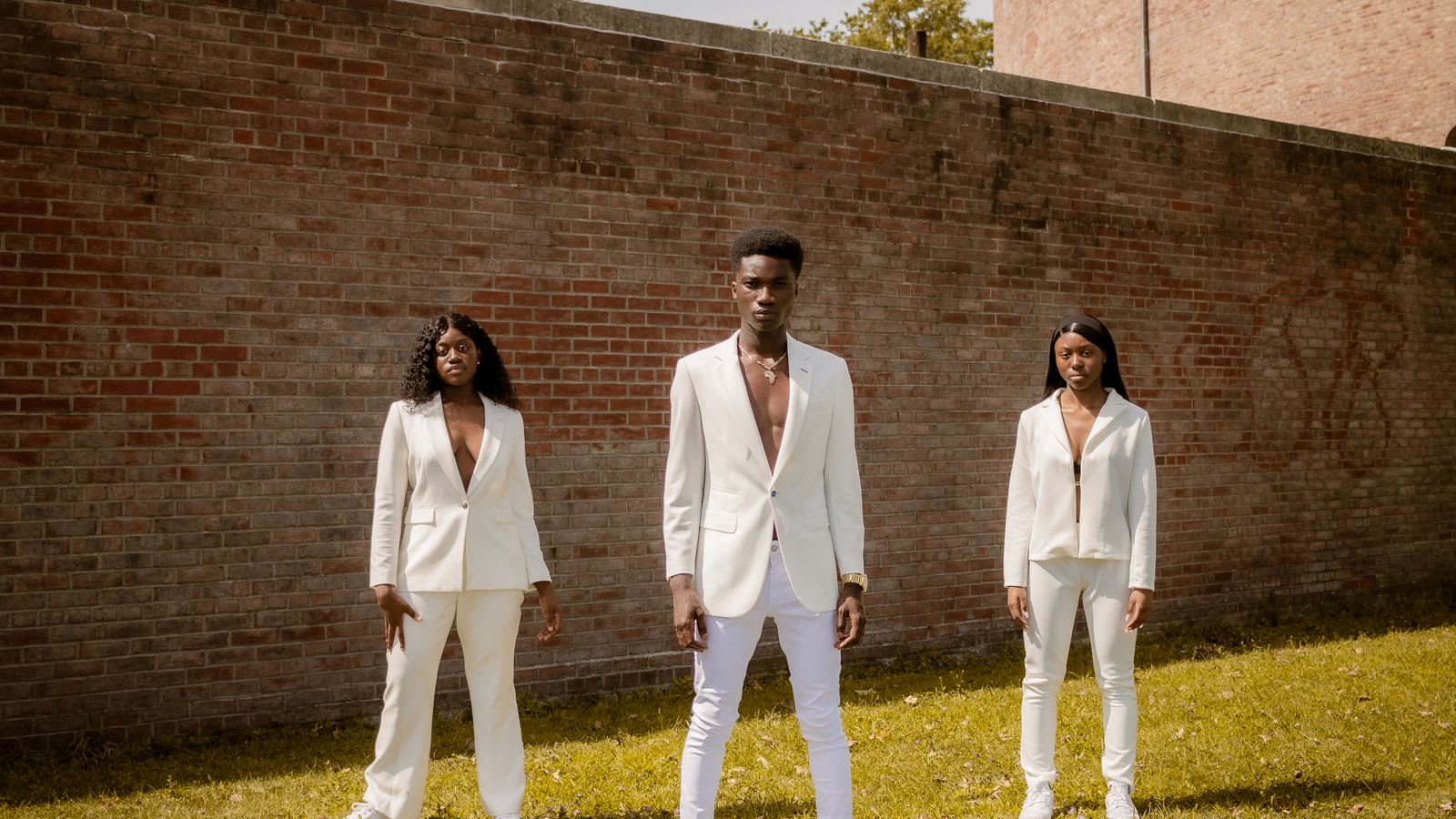 A group in white blazers photographed against a brick wall