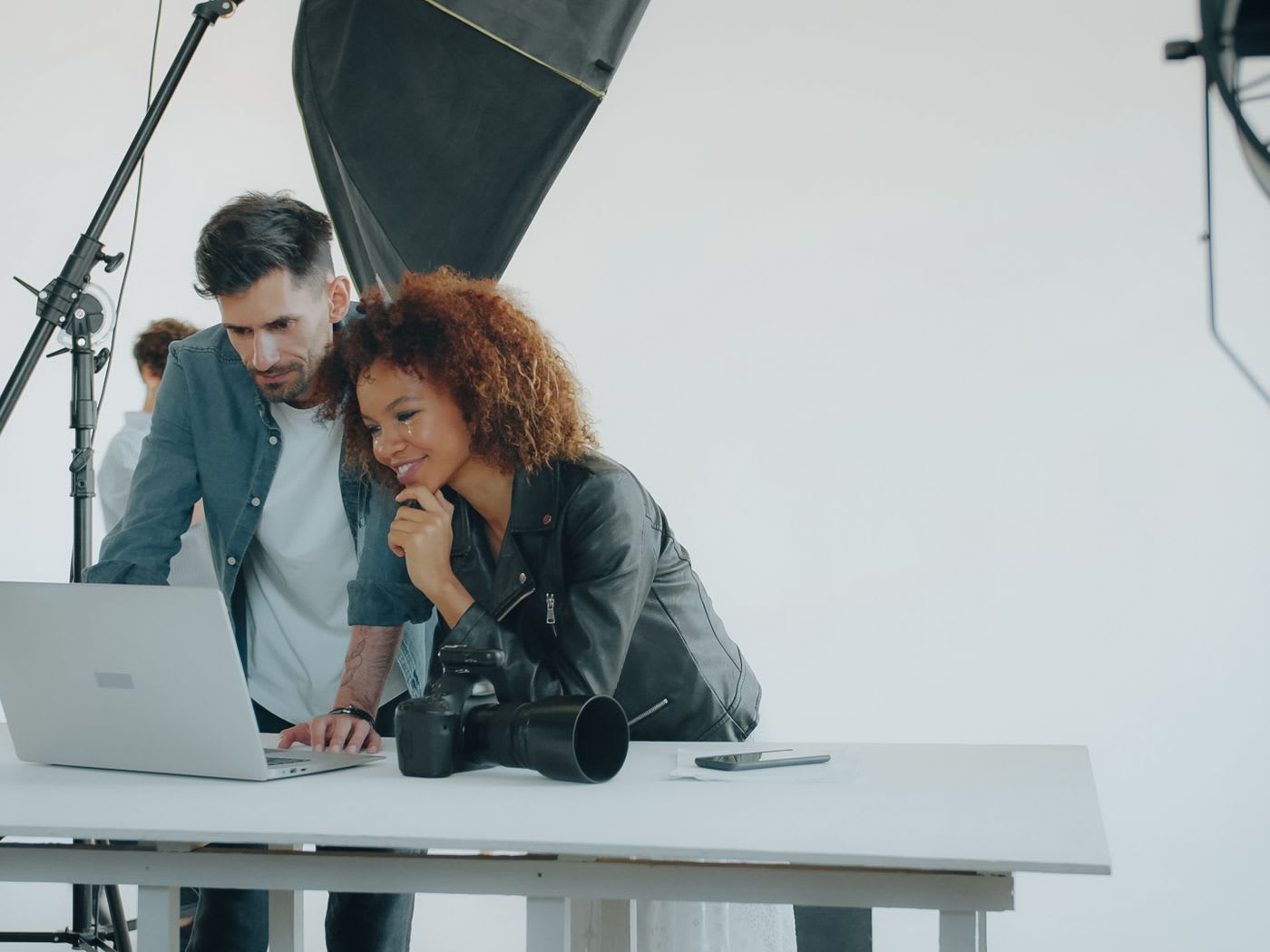 Two people reviewing work together on a laptop in a studio