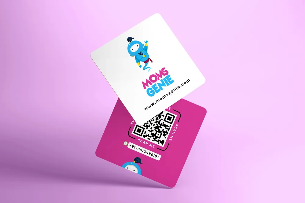 A MomsGenie card on lilac: a white front with Wishie and the wordmark, a magenta back with a scan-me QR code