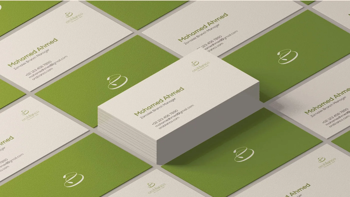 Oroblanco business cards in cream and green, scattered and stacked, each with the flowing mark