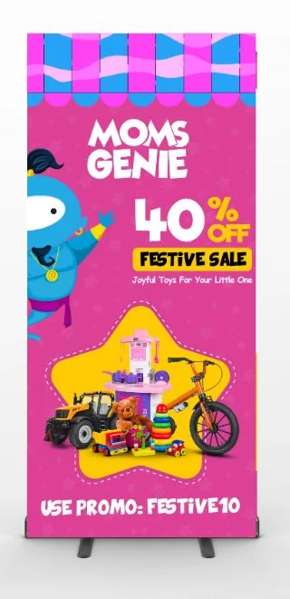 A bright pink MomsGenie festive sale standee with toys, a mascot and a promo code at the foot