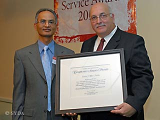 Kamal Duggirala, SYDA Foundation trustee, presents a certificate of merit to Bill Sipos.