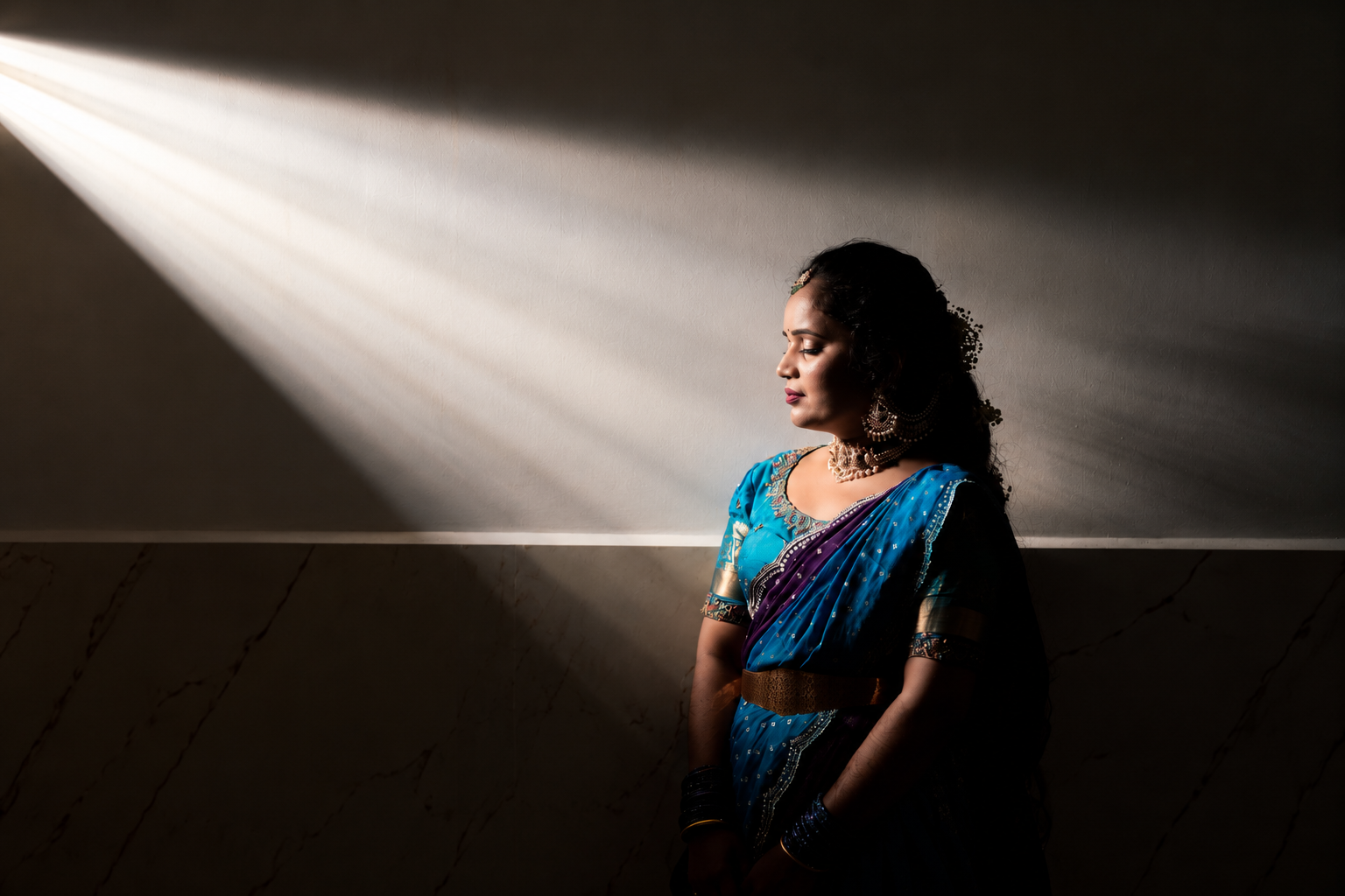 A bride in a red and gold saree, adjusting her wedding jewelry