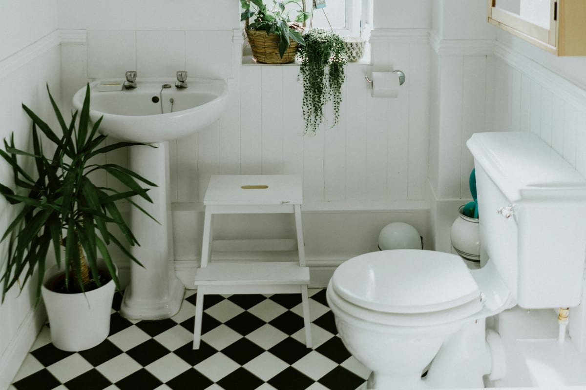 Bright white bathroom with a wall exhaust fan above the mirror