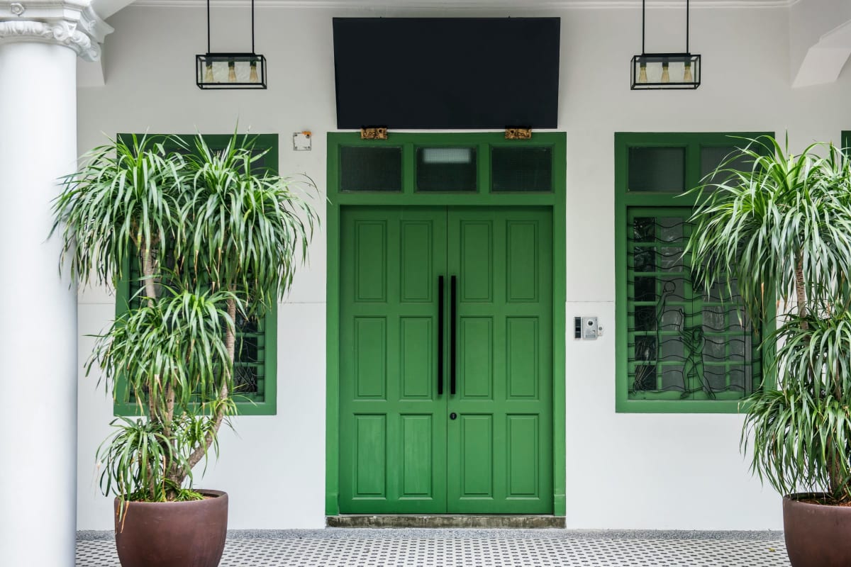 Green double entry doors between potted palms