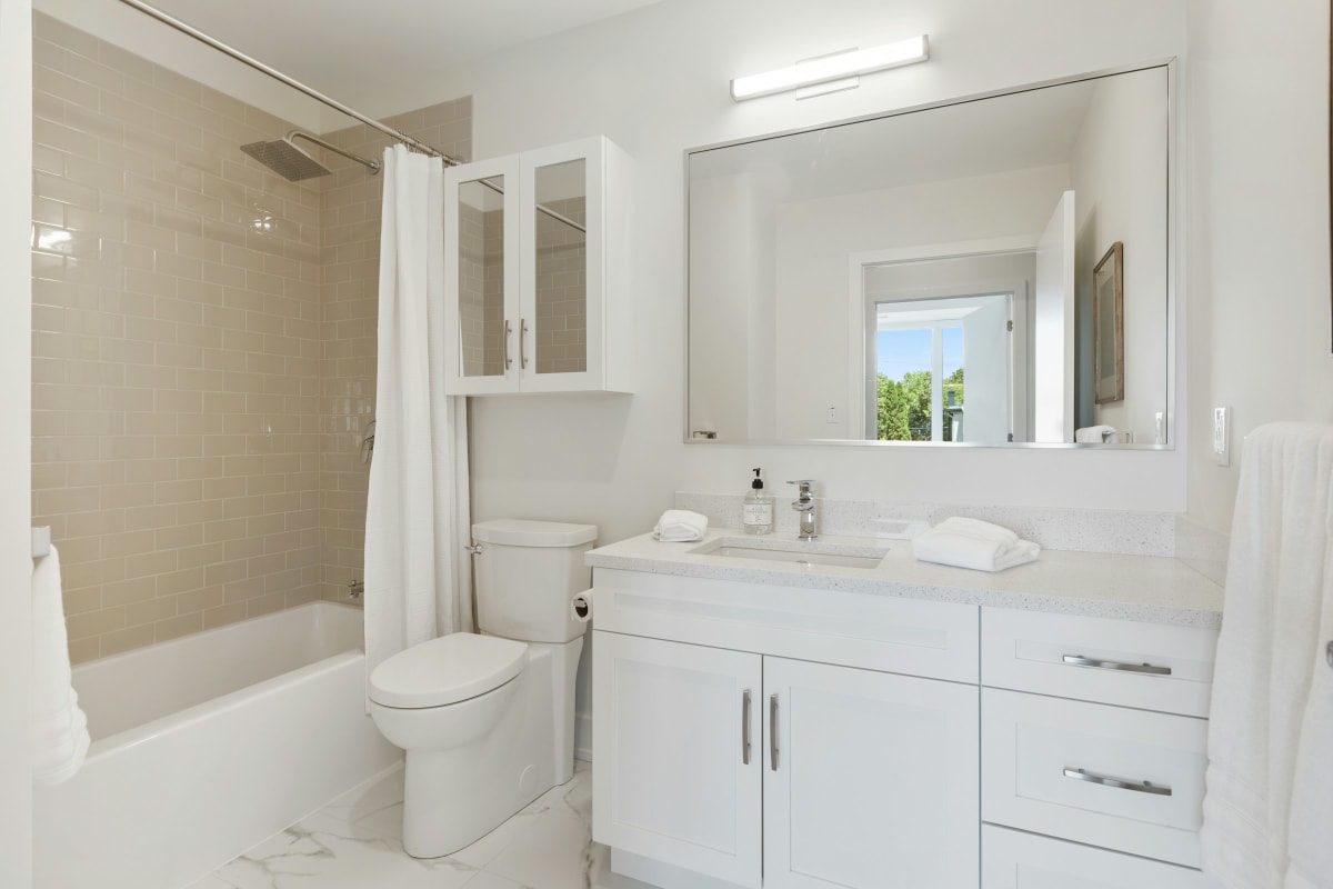 White bathroom with a toilet, tub and vanity
