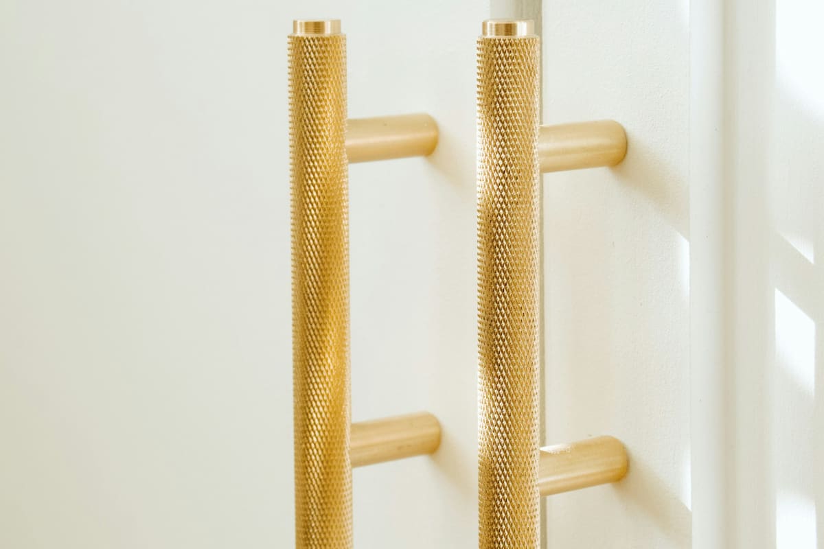 Knurled brass bar pulls on white cabinet doors