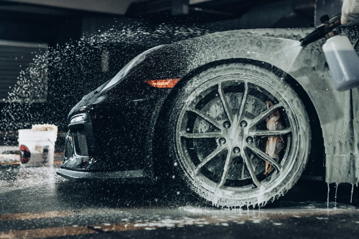 Washing a black sports car wheel with suds