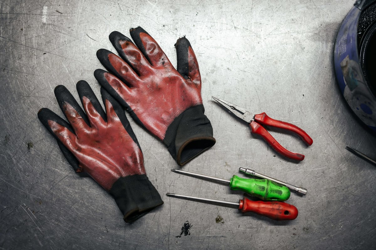 Red nitrile-dipped work gloves beside pliers and screwdrivers