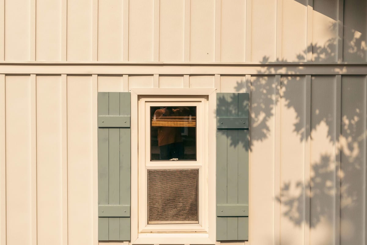 Board-and-batten wall with white window trim and green shutters
