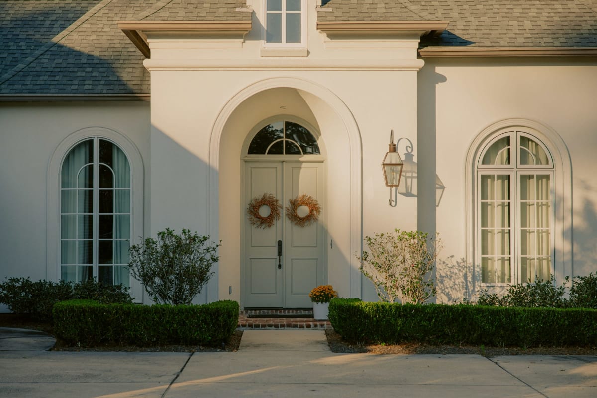 Cream house with crisp white trim around arched windows and the front door