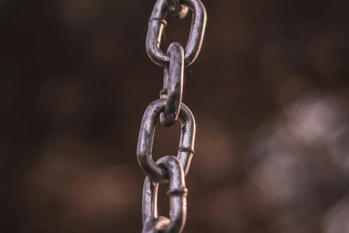 Steel chain hanging against a dark background