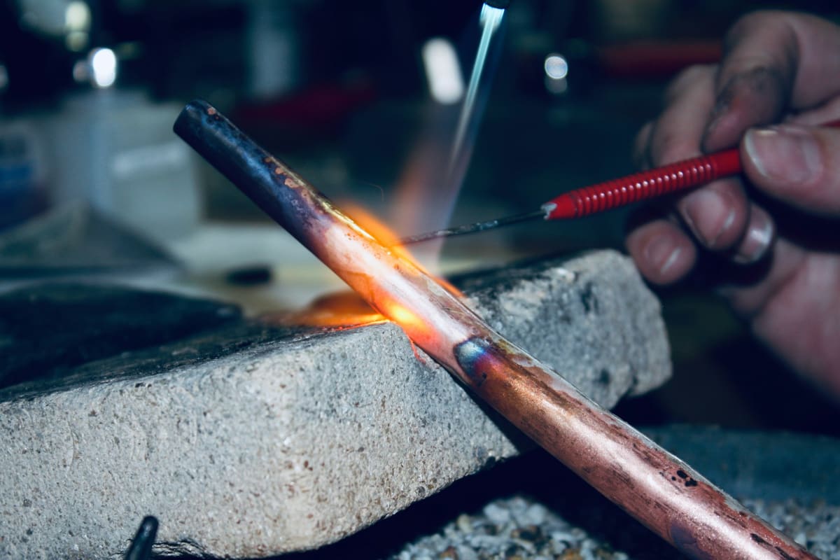 Soldering a copper pipe joint with a torch flame