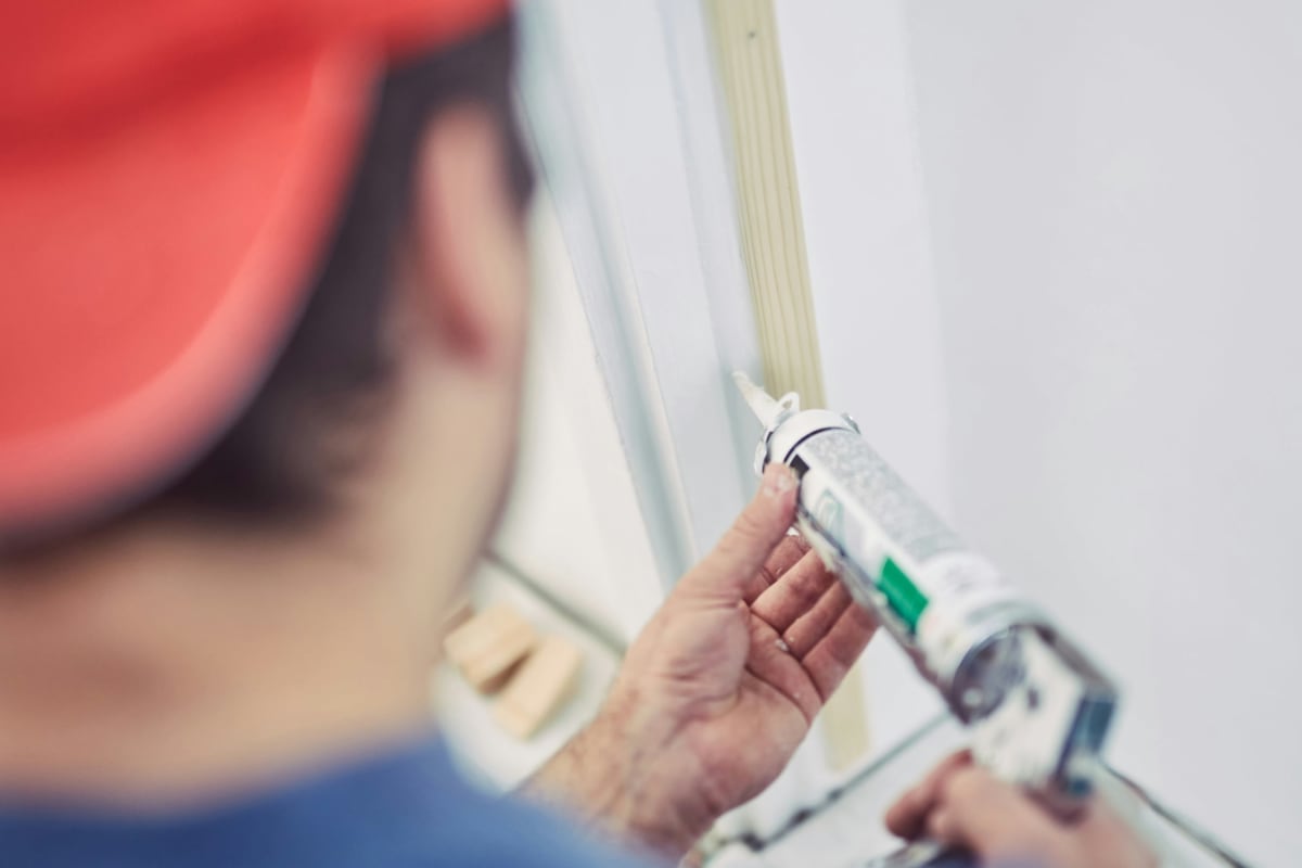 Close-up of hands loading a caulk tube into a gun