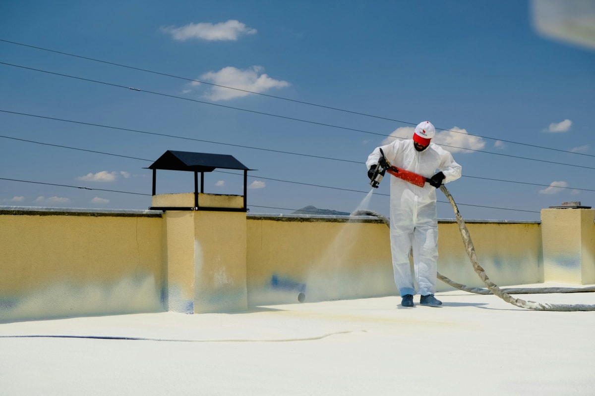 Worker spraying a white coating onto a flat roof