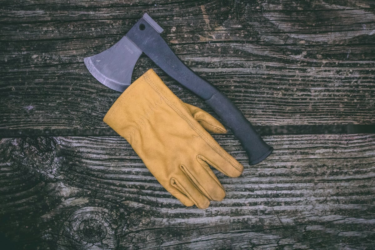 Yellow leather work glove beside a hatchet
