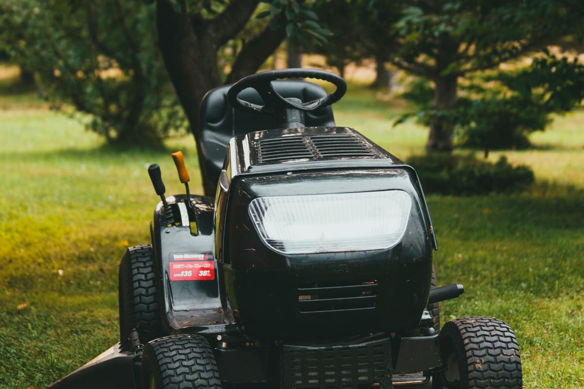 Riding mower parked under shade trees