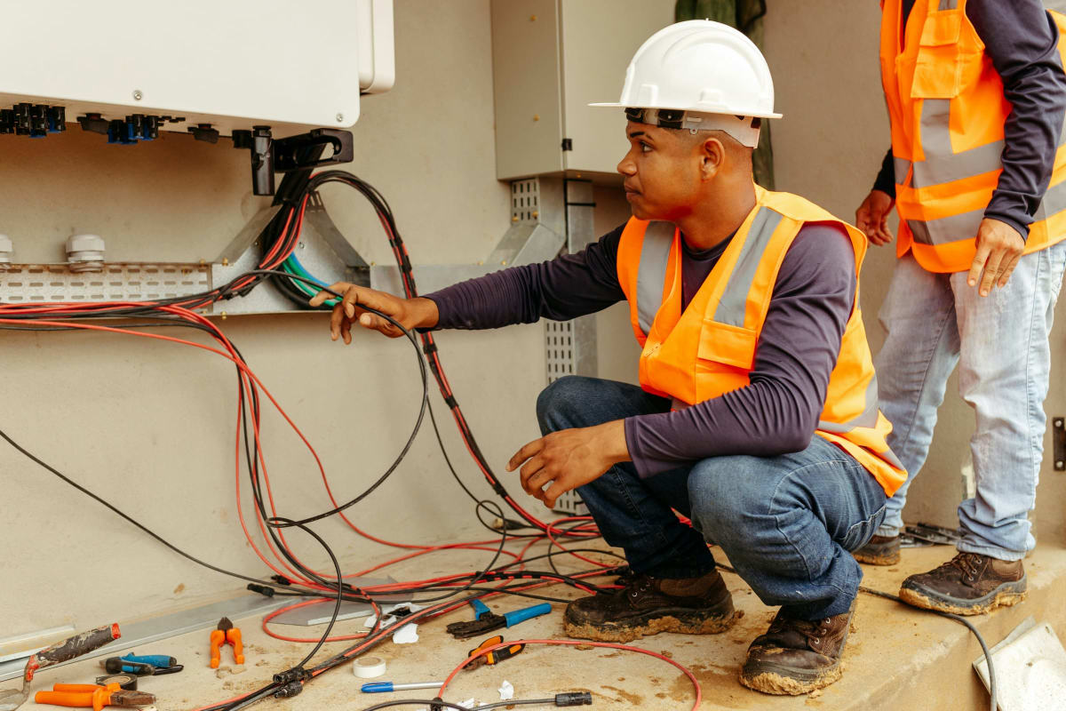 Electricians in hard hats running wire on a job site