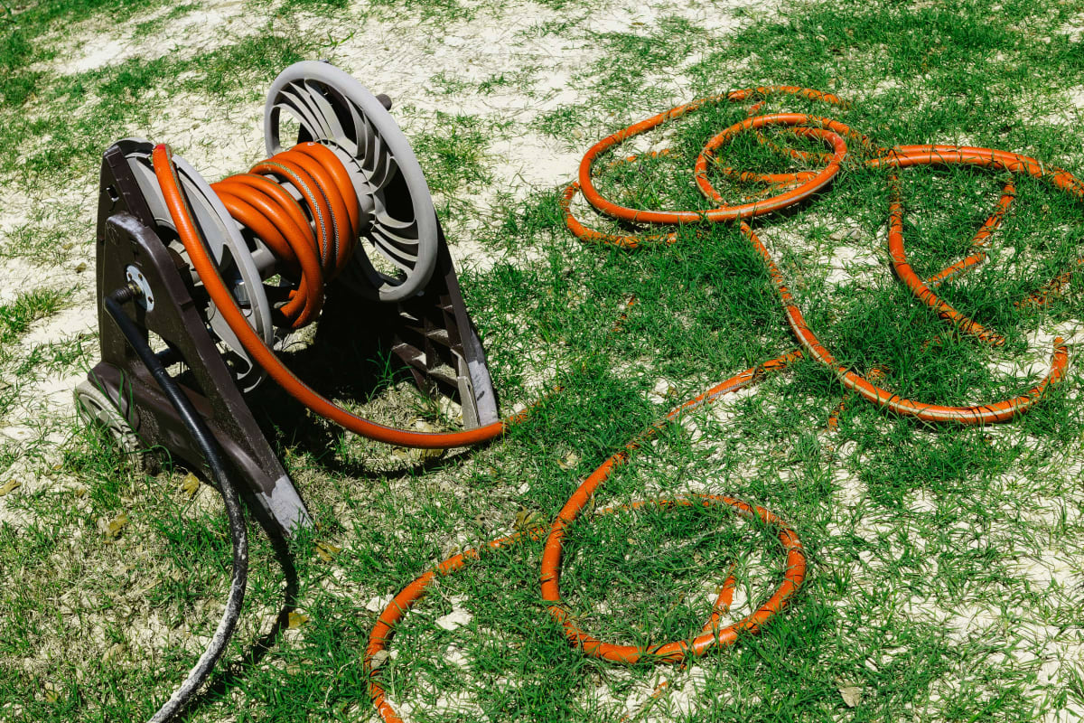 Orange extension cord unwound from a reel on the lawn