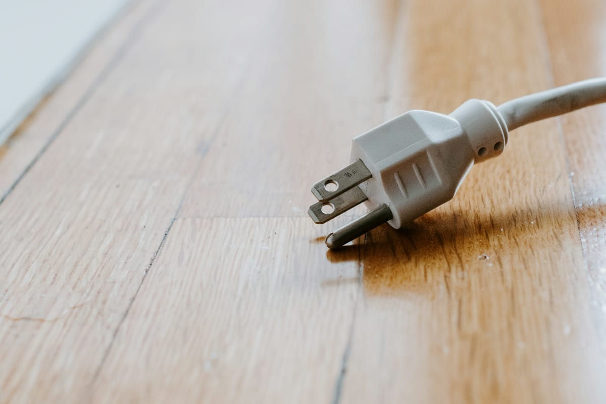 Extension cord plug lying on a wood floor