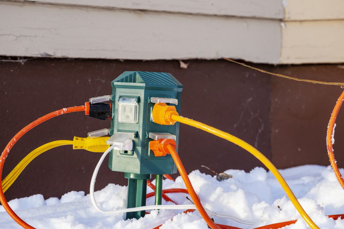 Extension cords plugged into an outdoor power stake in the snow
