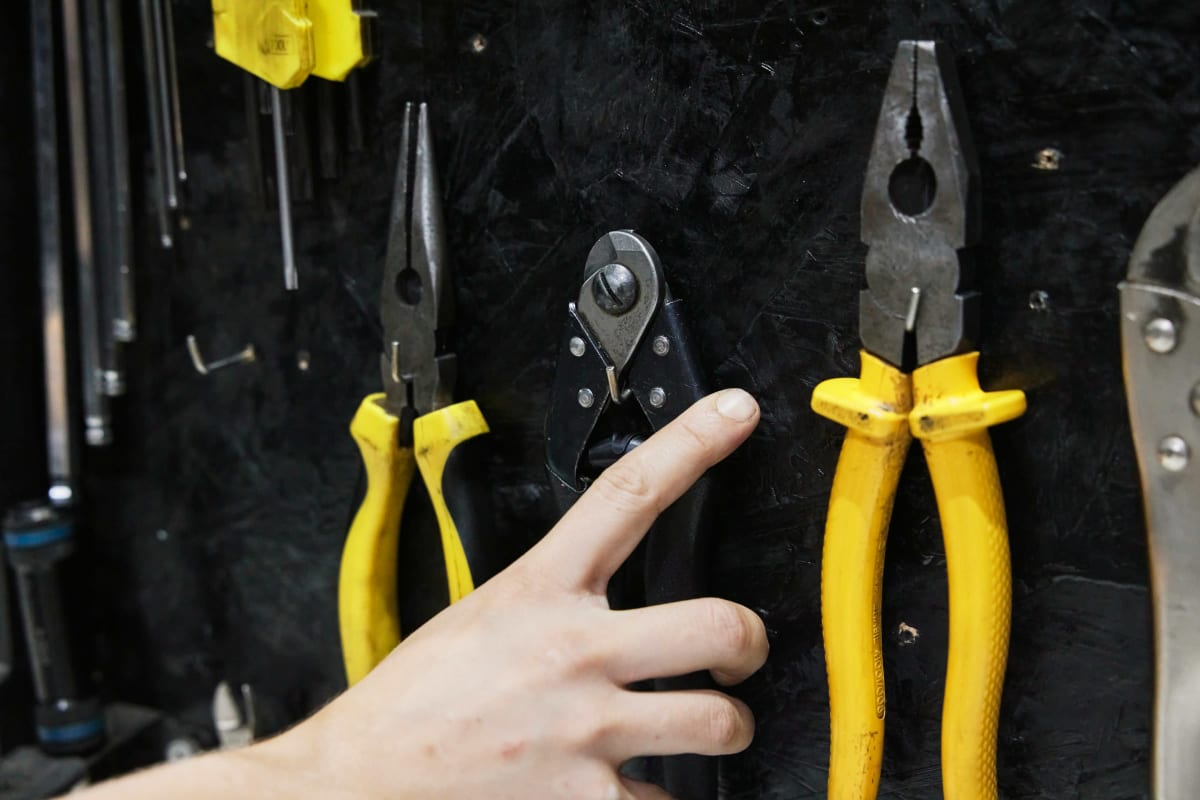 Reaching for pliers on a tool wall