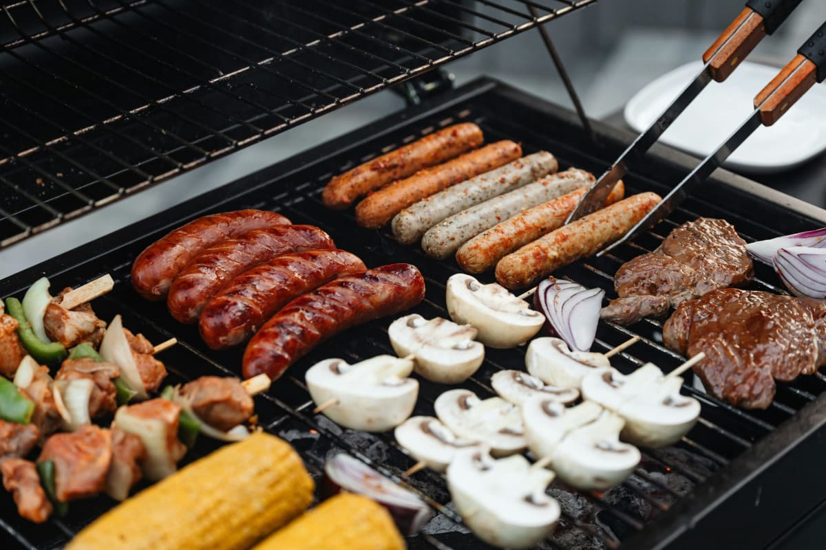 Sausages, corn, mushrooms and steak on a grill