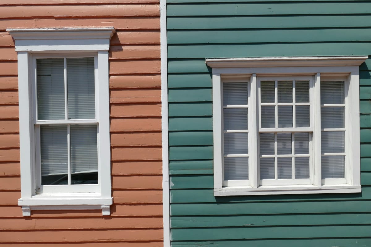 White-trimmed windows on two colorful sided houses