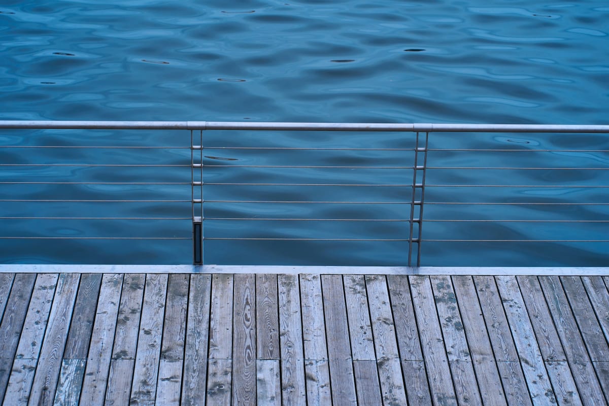 Horizontal cable railing along a weathered deck by the water