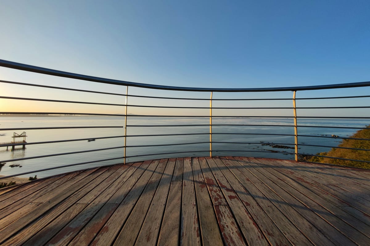 Wood deck with cable railing overlooking the water at sunset