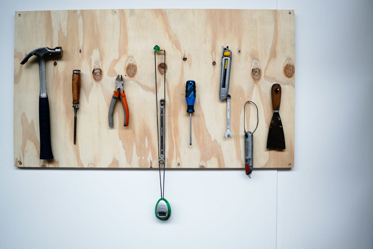 Hand tools hung on hooks on a plywood board