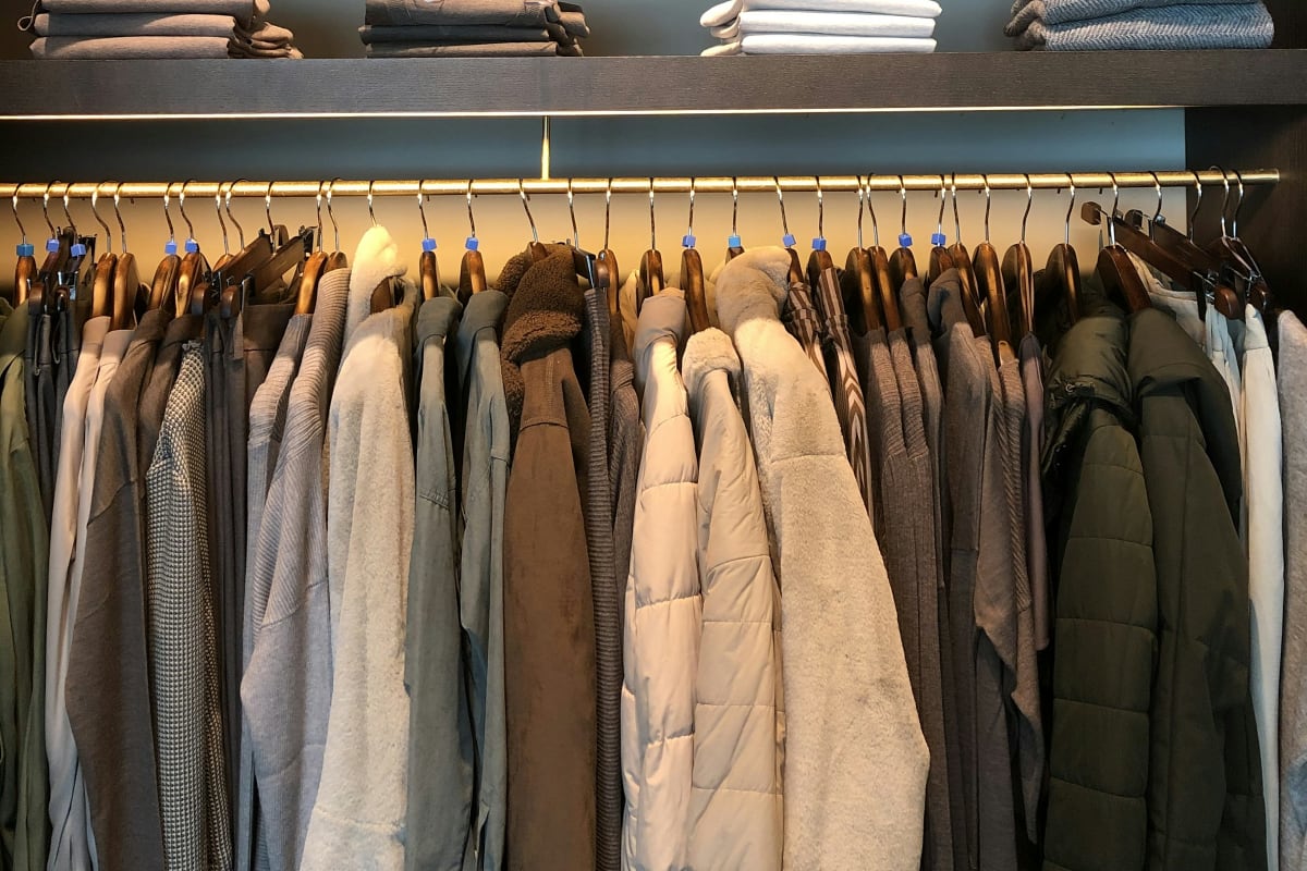 Closet rod of clothes under a shelf of folded sweaters