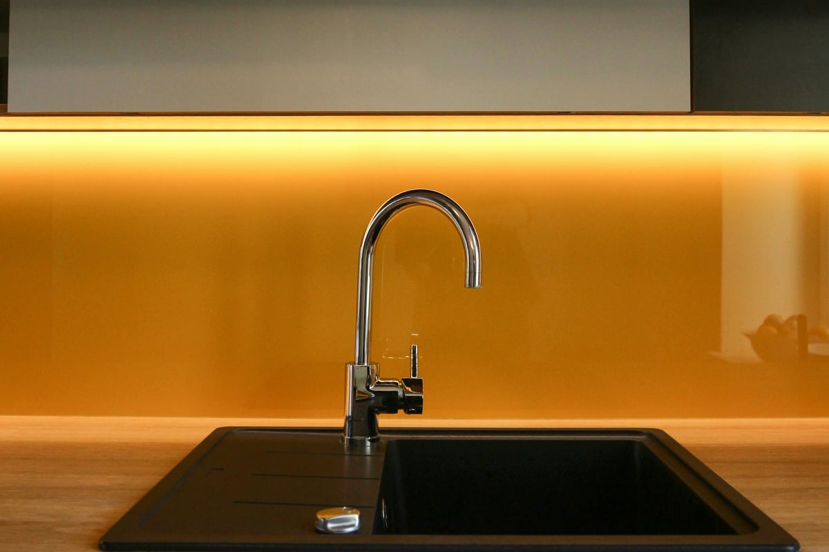 Arched faucet over a sink with warm backlighting