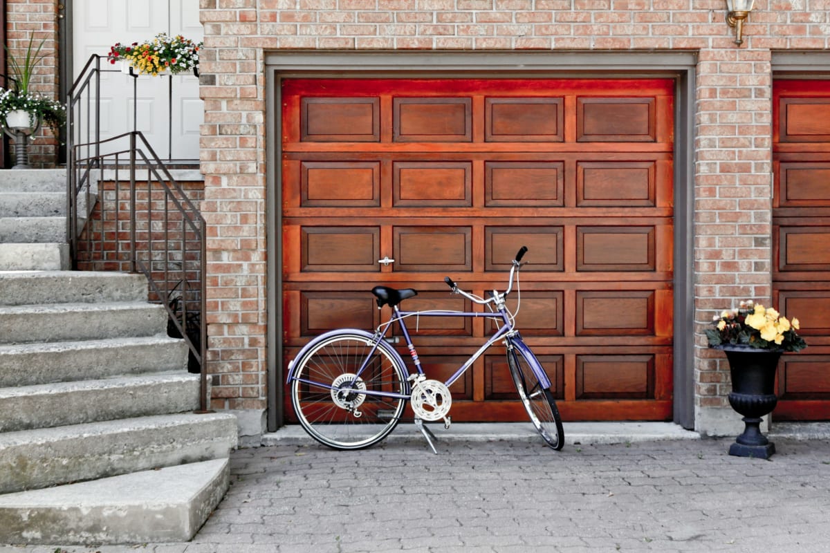 Wood garage door on a brick home with a bike out front