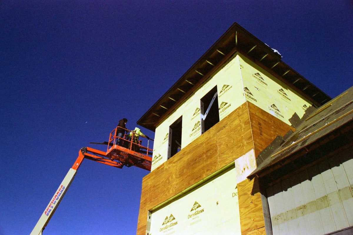 Builders on a lift at a wrapped new home