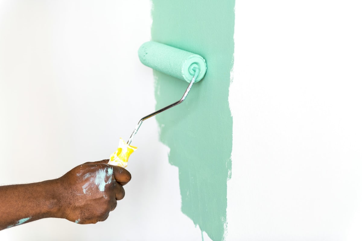 Rolling mint green paint onto a wall