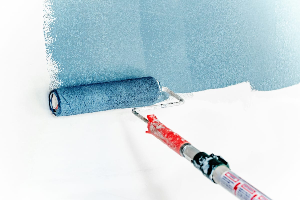 Rolling blue paint onto a white wall