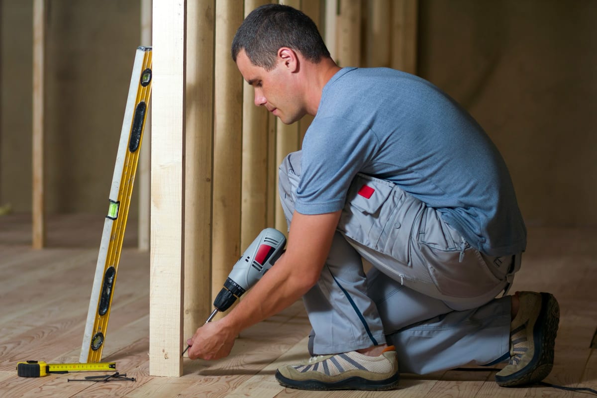 Carpenter fastening a stud with a level close by