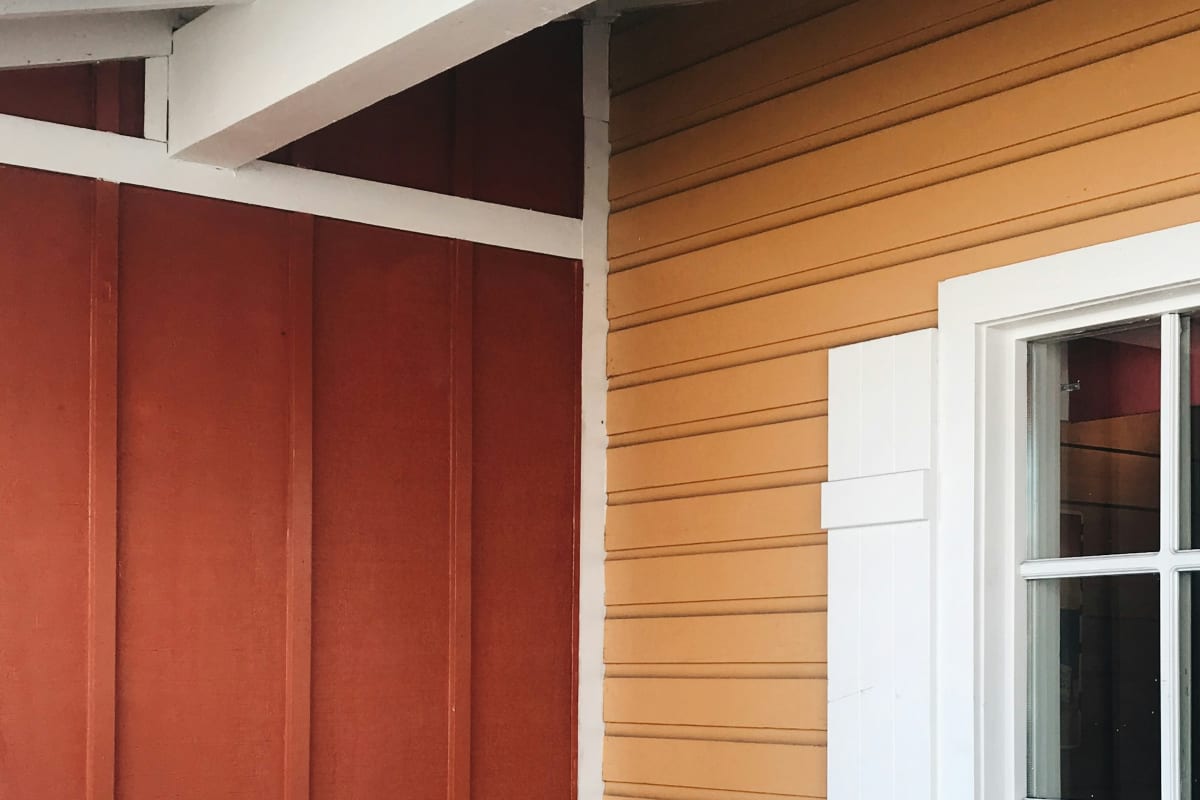 Colorful lap and vertical siding beside a white-trimmed window