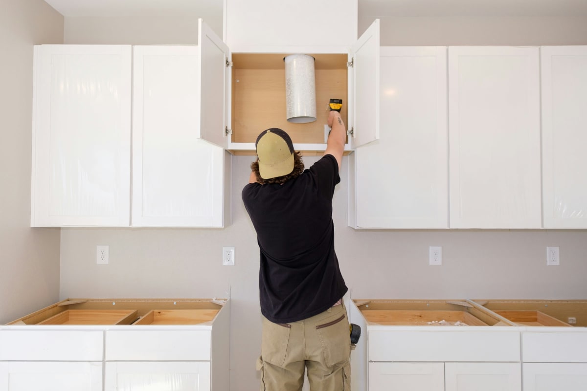 Installer hanging white upper cabinets