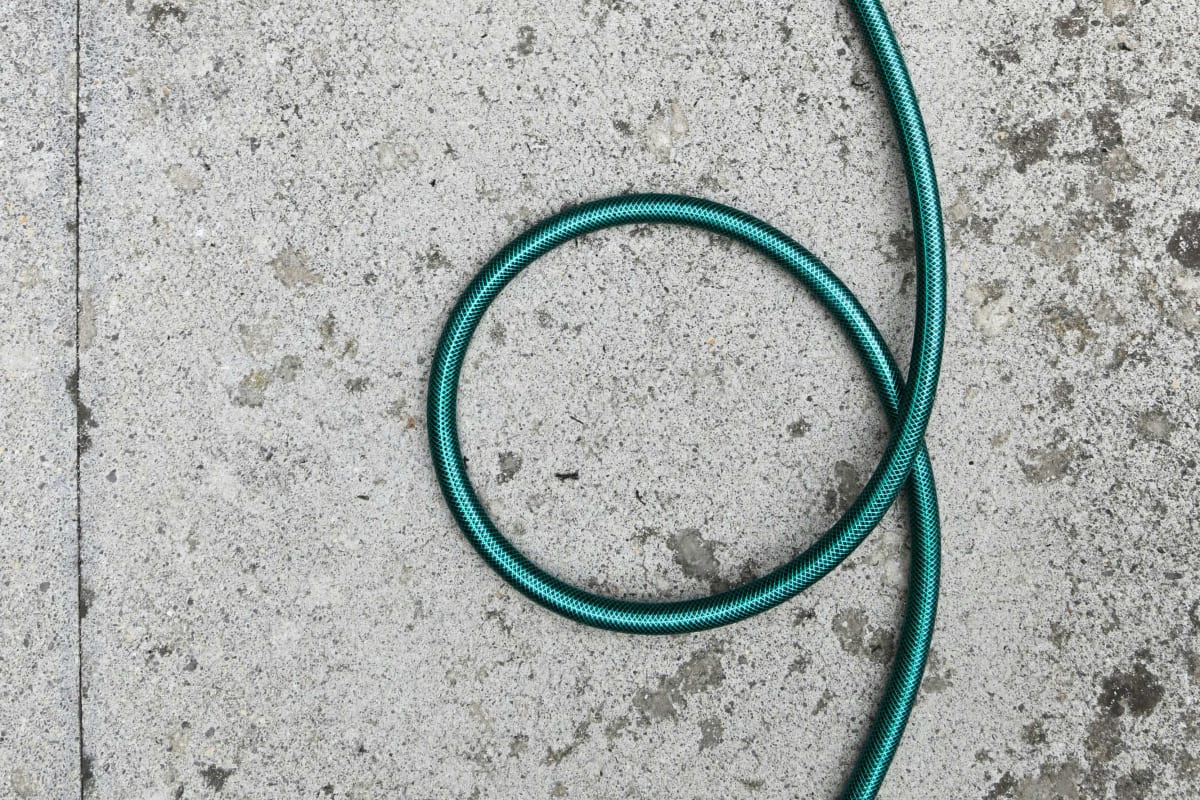 Green hose snaking across a patio