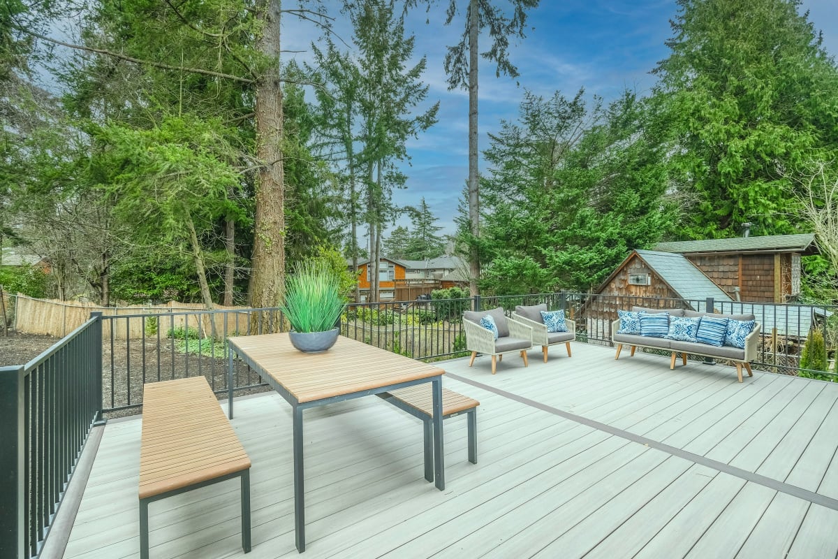 Deck with black metal railing and patio furniture among the trees