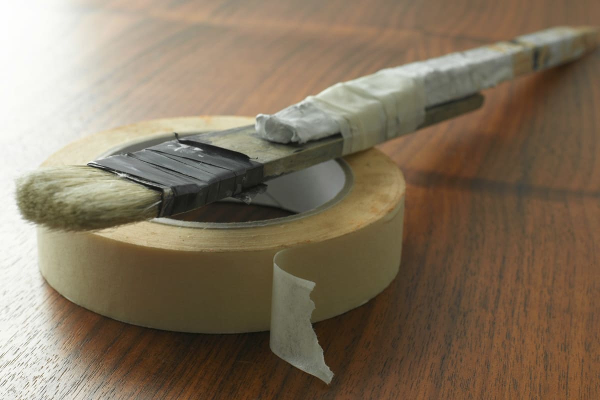 Paintbrush resting on a roll of painters tape