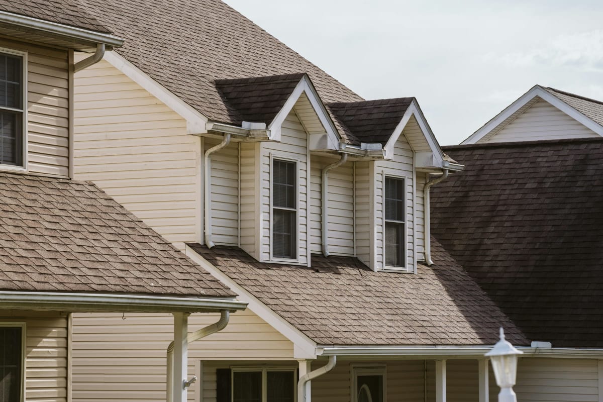 Two-story home with dormers and a brown shingle roof