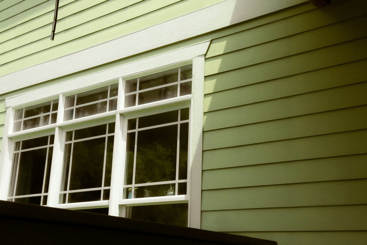Green lap siding around white-trimmed windows