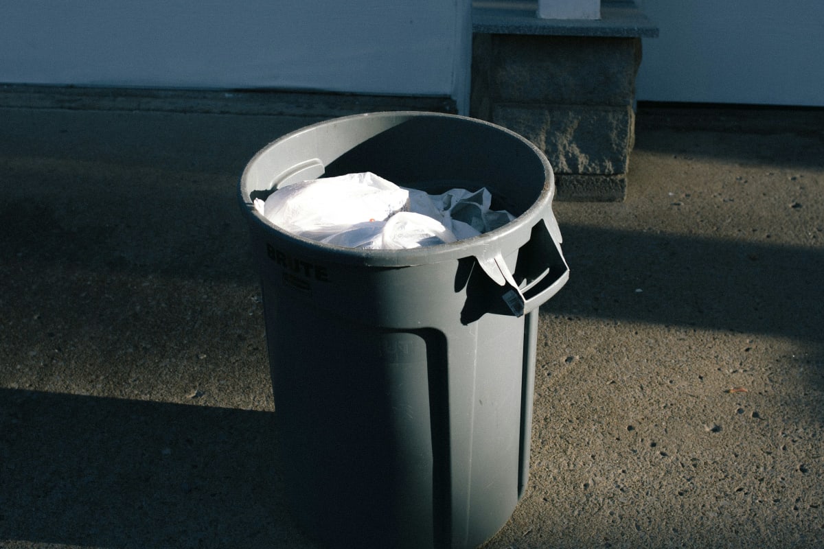 Trash can with a full bag by the curb